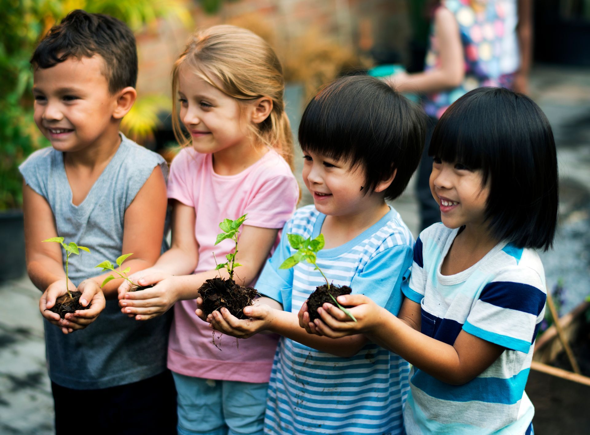 Group of four children holding seedling plants in their hands