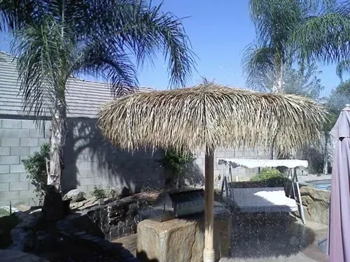 A thatched umbrella is sitting next to a golf cart.