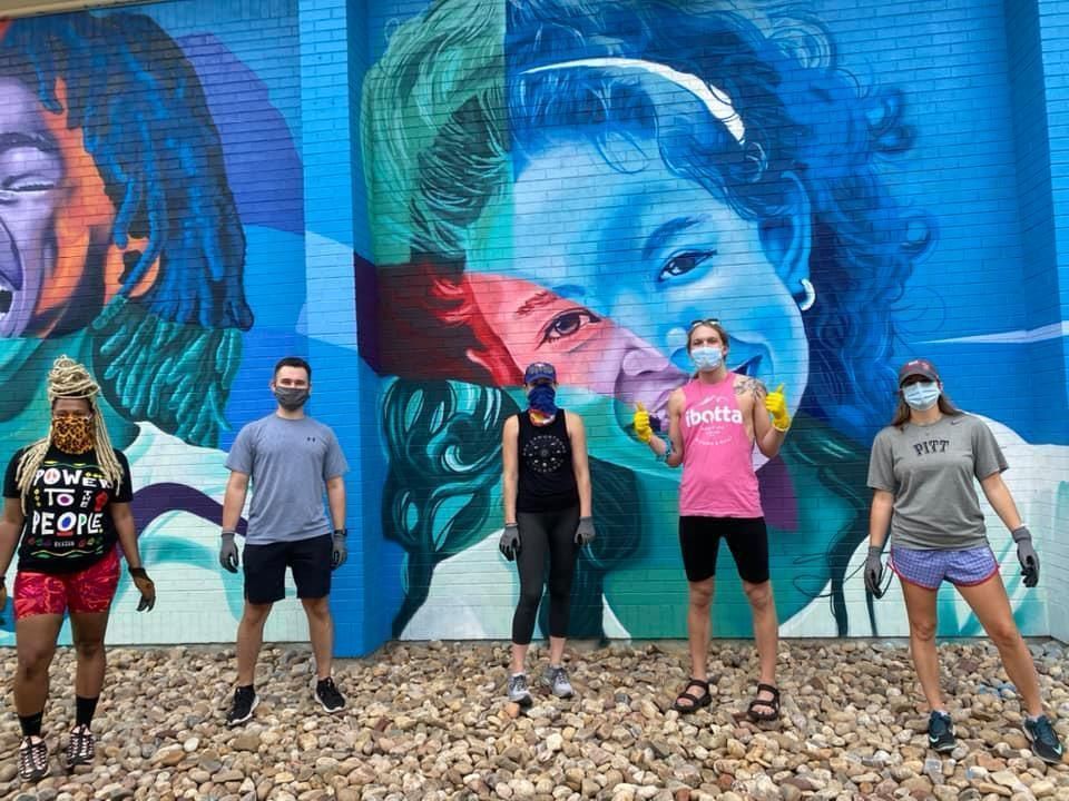 A group of people are standing in front of a large mural.