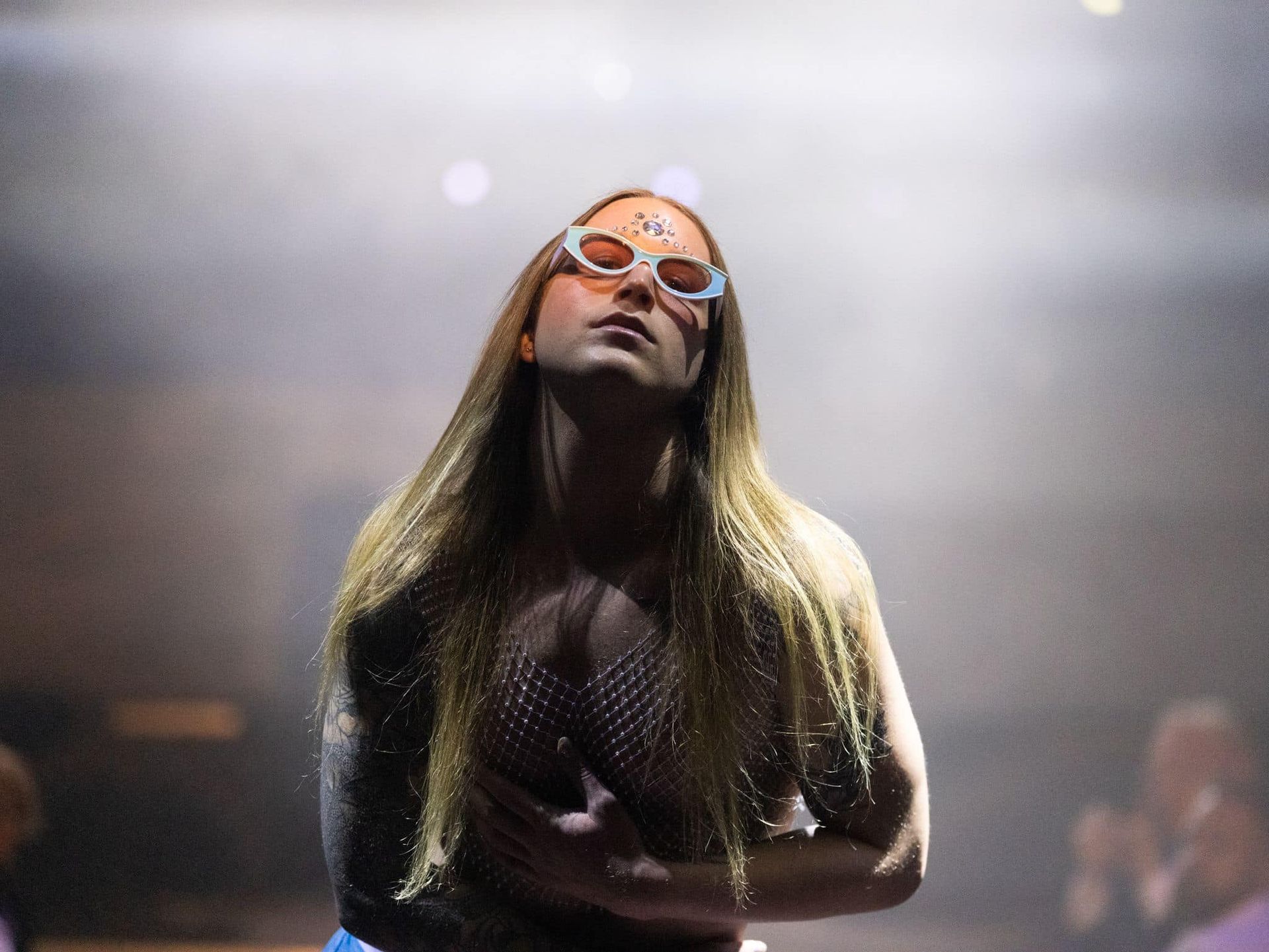 A woman wearing sunglasses is singing into a microphone on a stage.