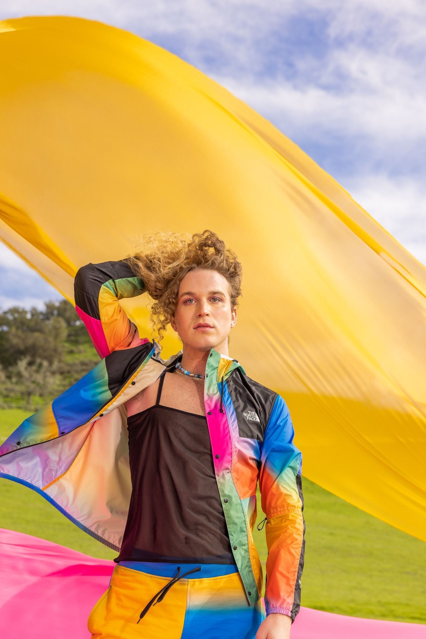 A young man in a colorful jacket is holding a large yellow flag for a NorthFace photo shoot.