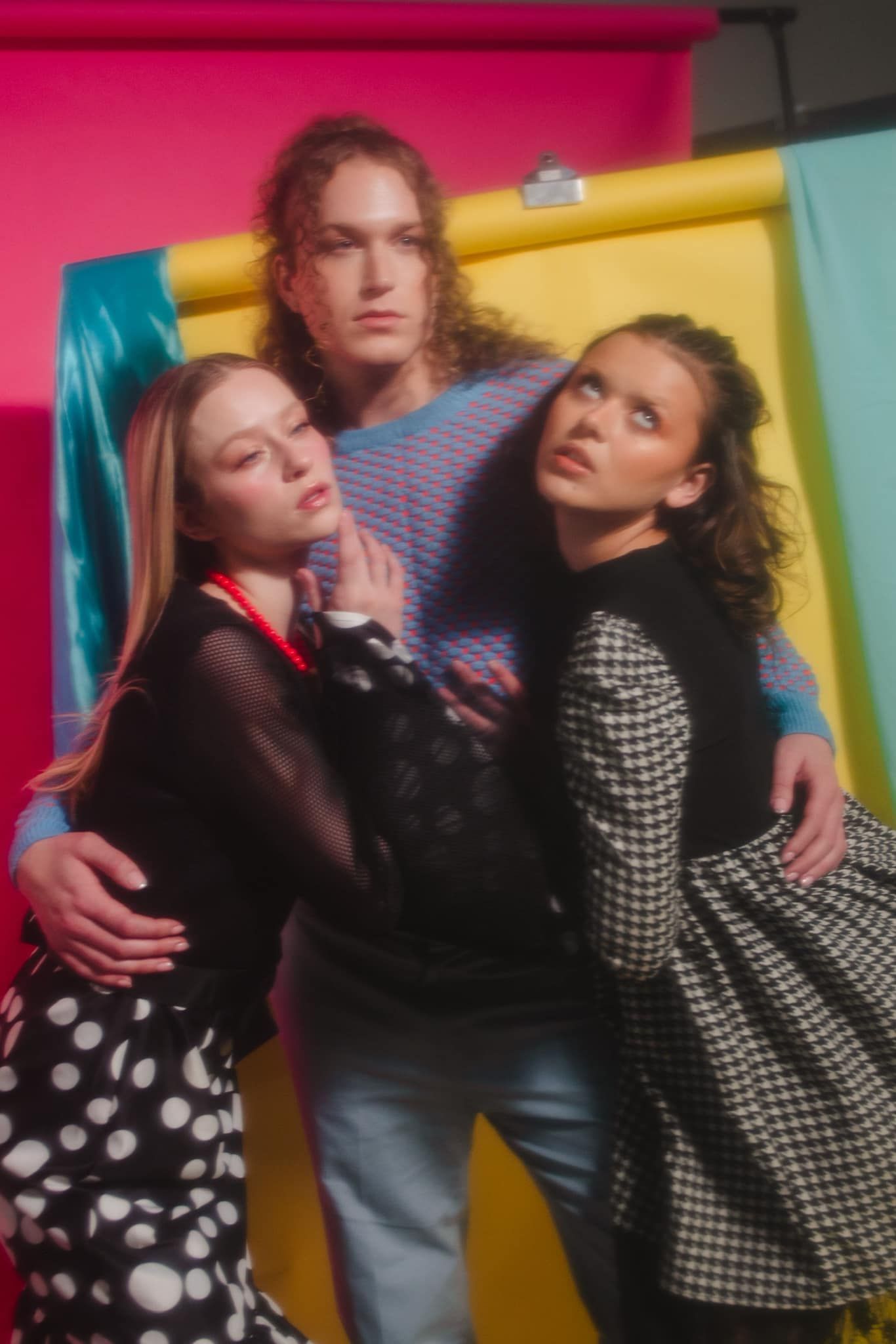 A man and two women are posing for a picture in front of a colorful background.