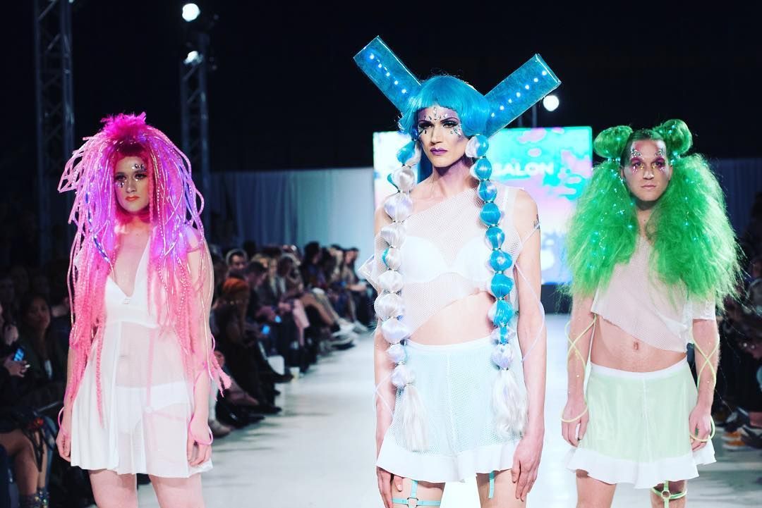 Three models are walking down a runway at a fashion show.