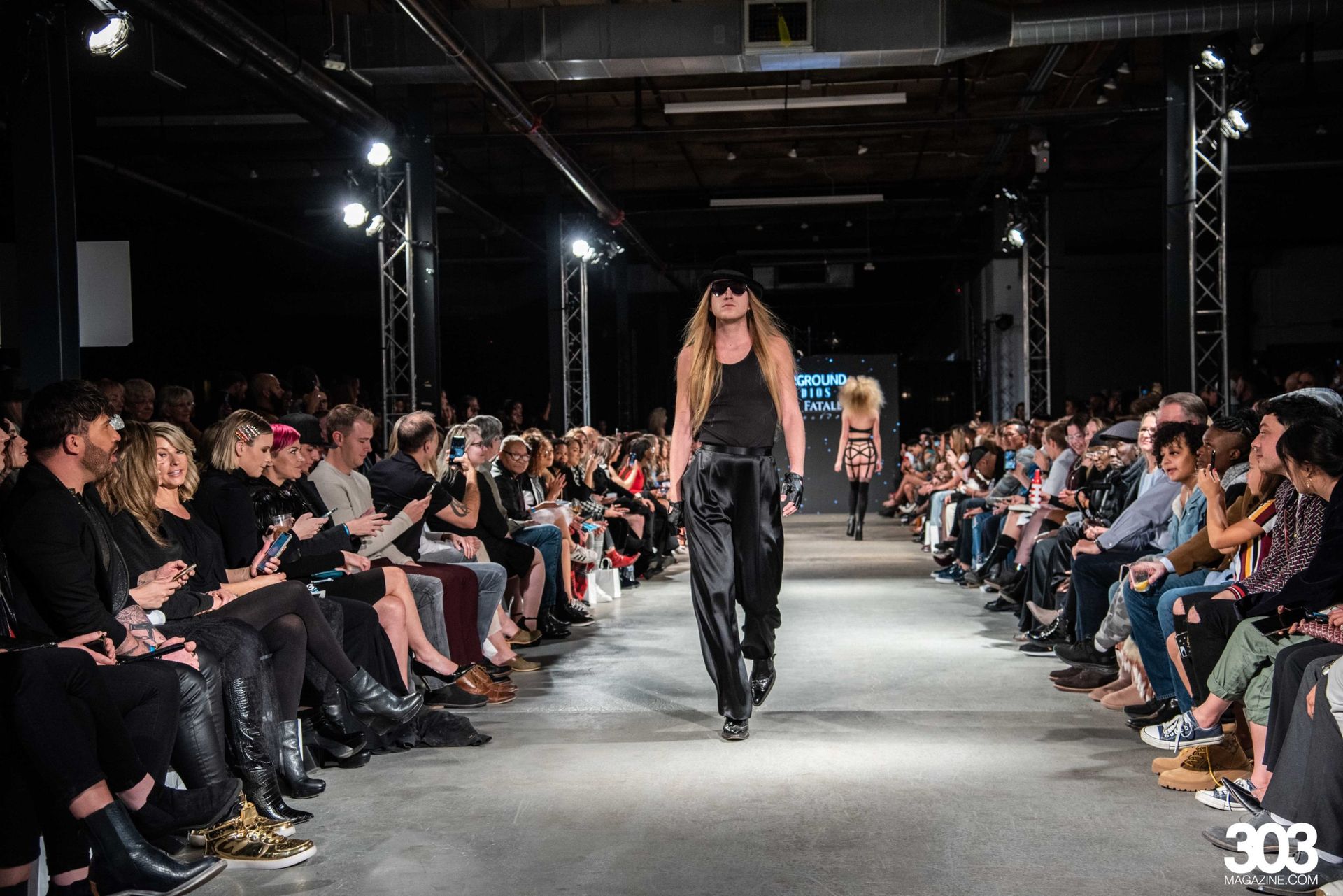 A woman is walking down a runway at a fashion show.