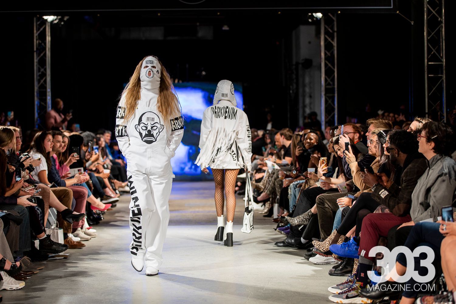 A group of models are walking down a runway at a fashion show.