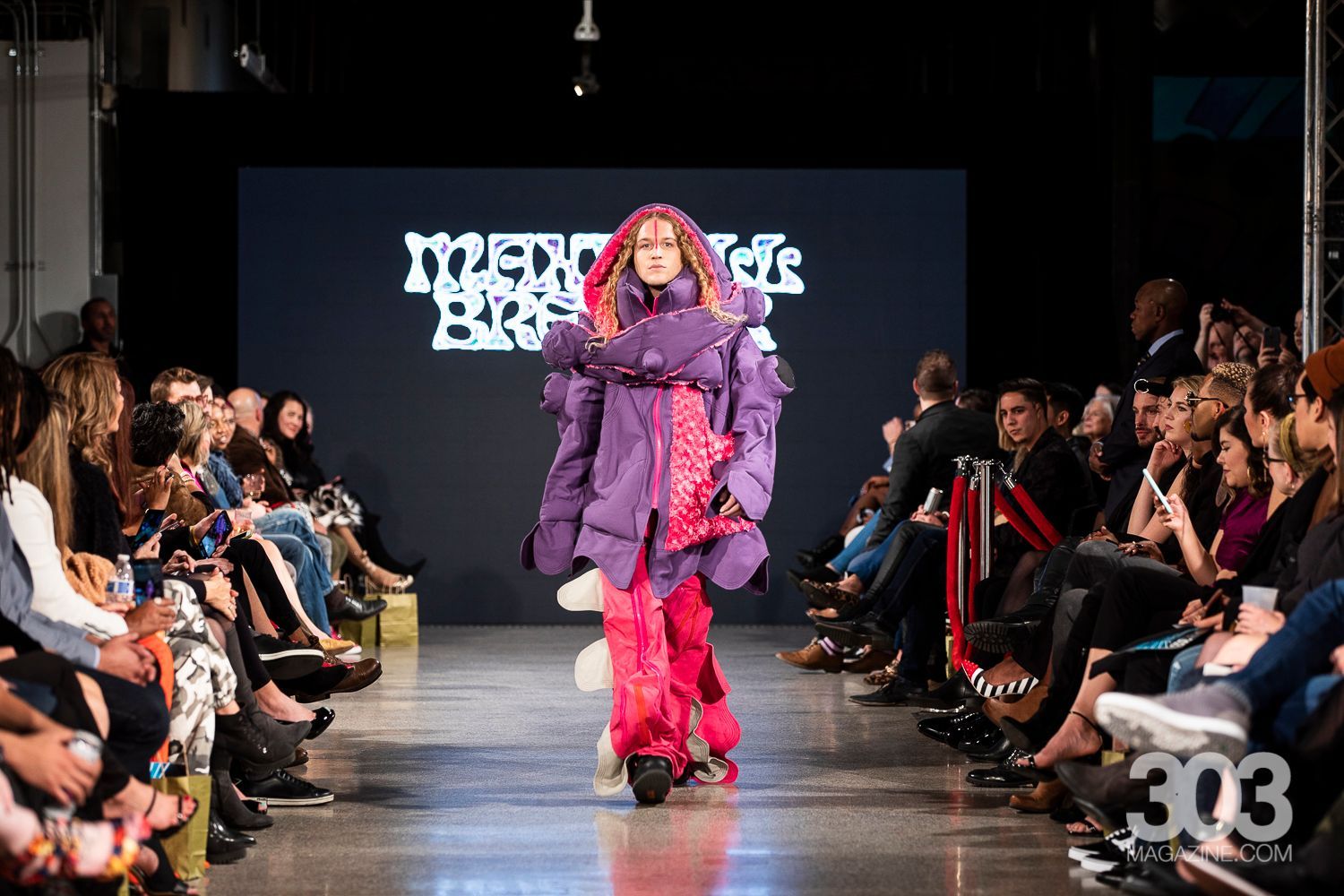 A model is walking down the runway at a fashion show.