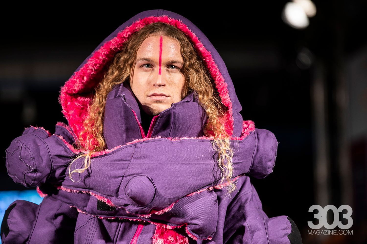 A woman is wearing a purple jacket with a red hood.