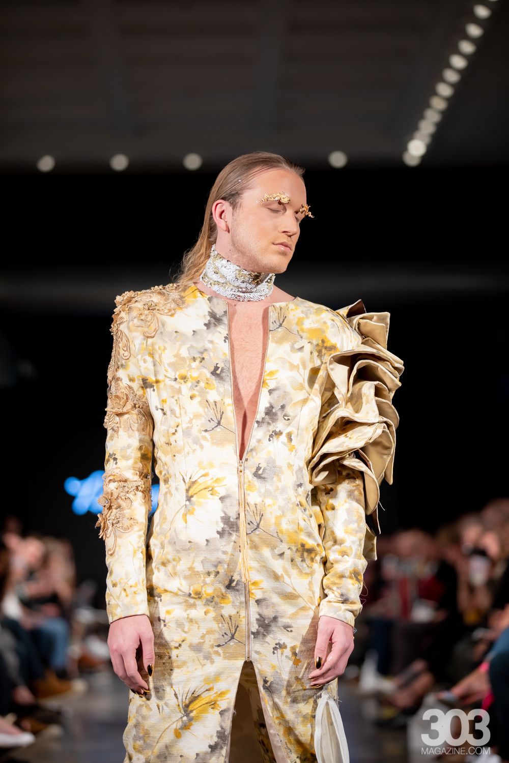 A model is walking down the runway at a fashion show wearing a very fancy dress.