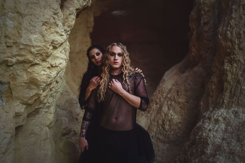 Scotty posing with a woman as they model for a halloween-themed photoshoot in a cave