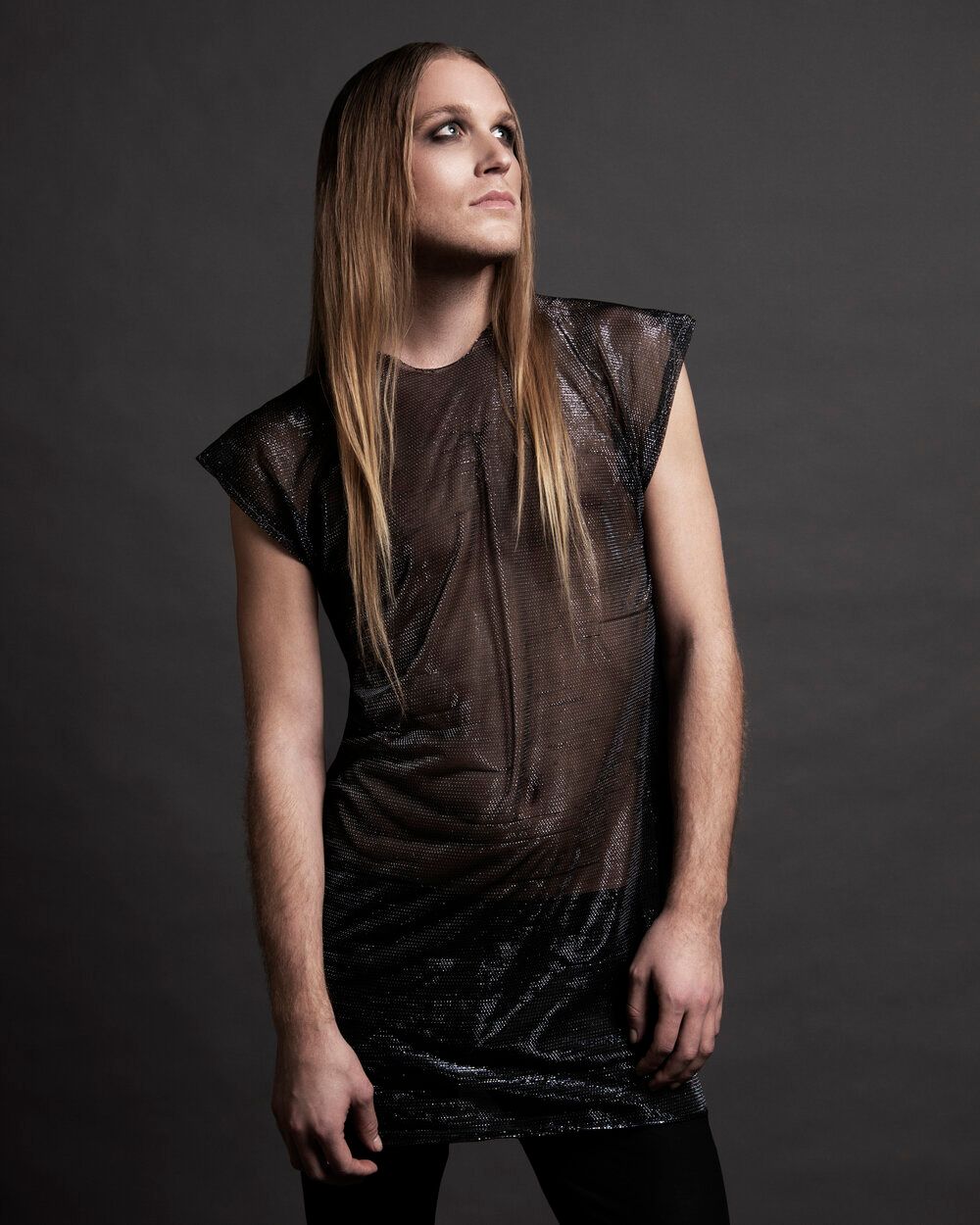 A woman with long hair is wearing a black dress for a photoshoot.
