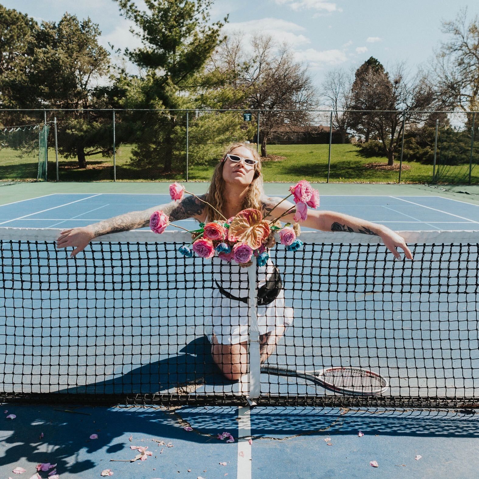 Scotty posing as a model on a tennis court with flowers for a photoshoot