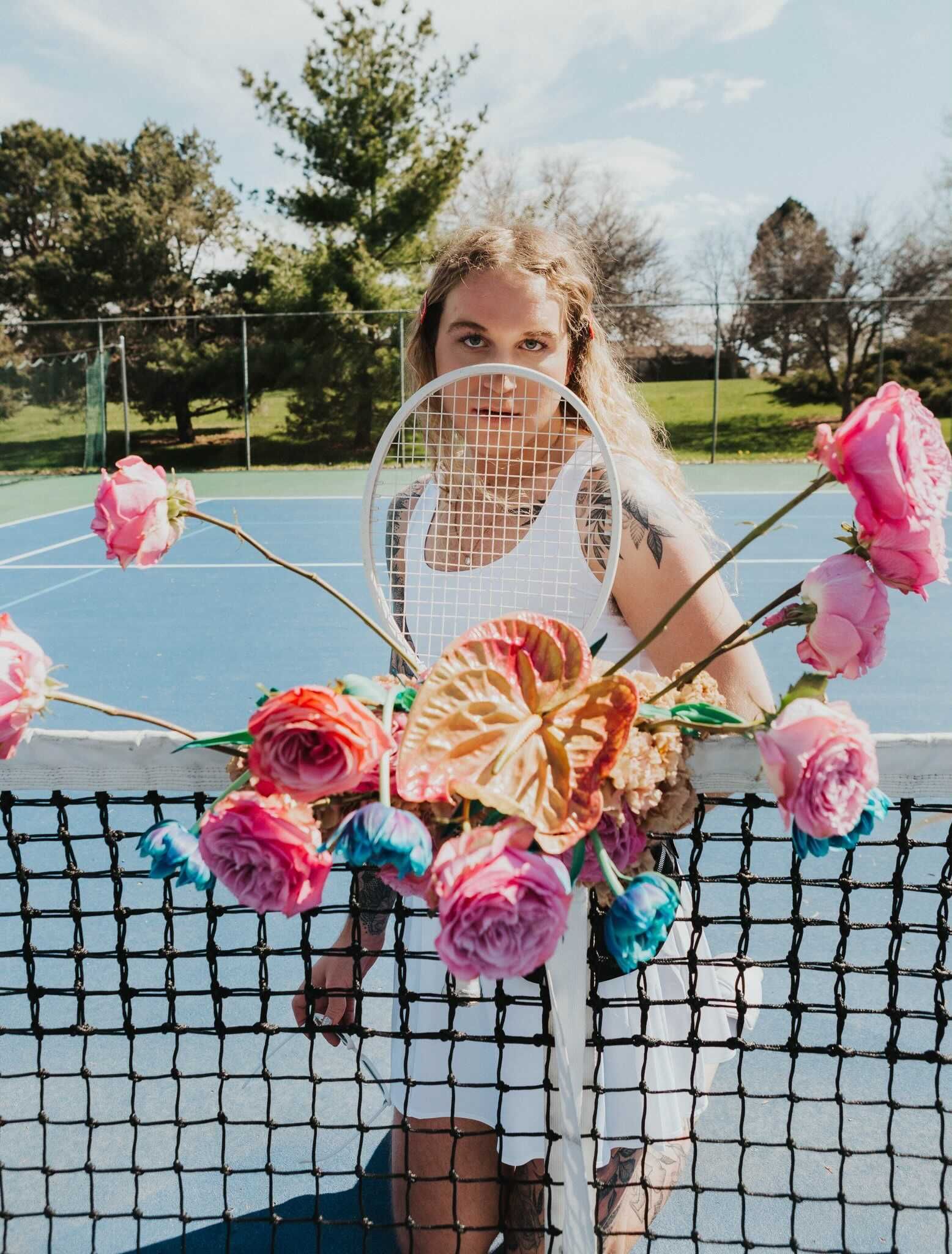 Scotty posing as a model on a tennis court with flowers for a photoshoot