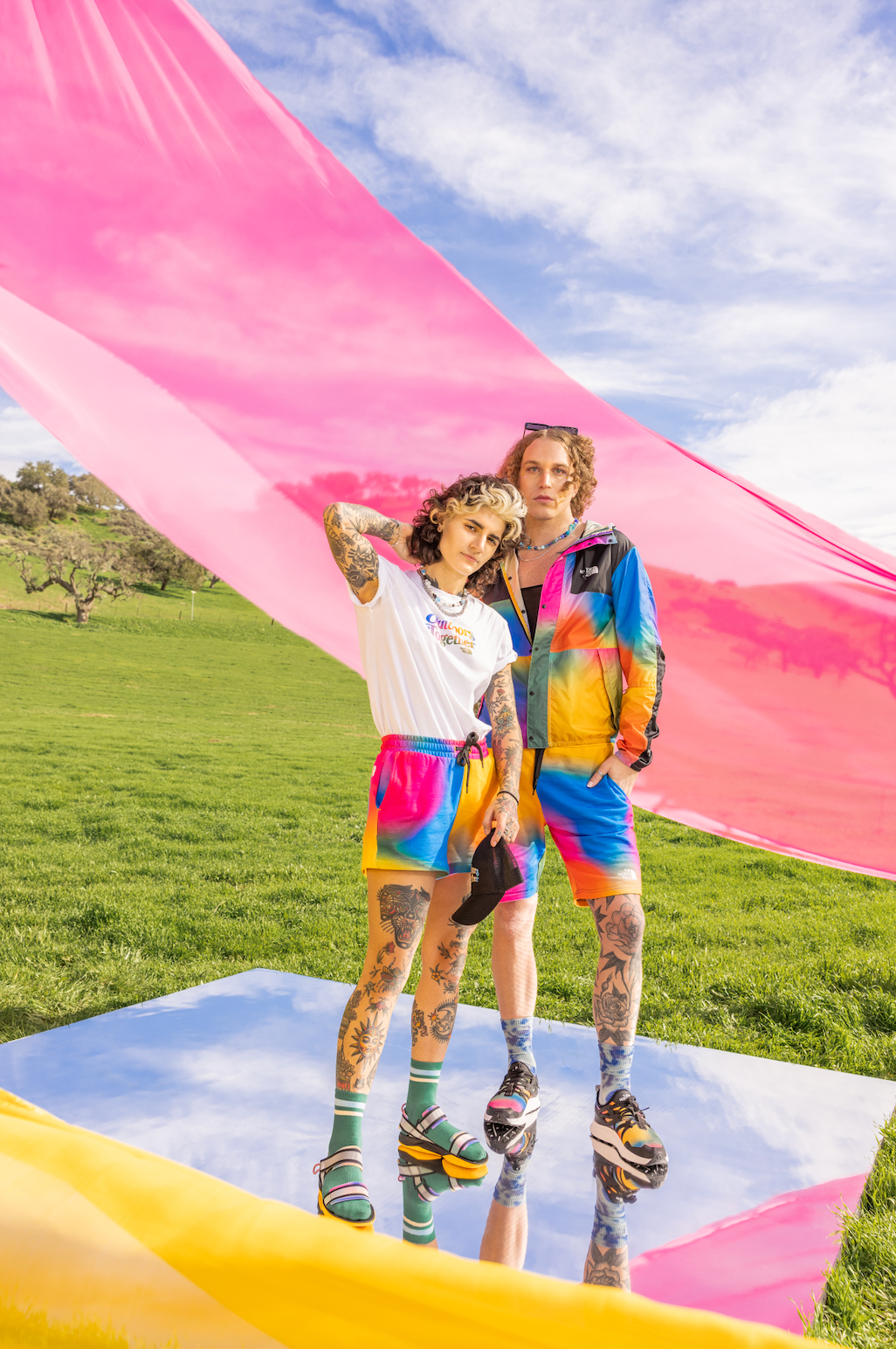 A man and a woman are standing next to each other in a field for a NorthFace photo shoot.