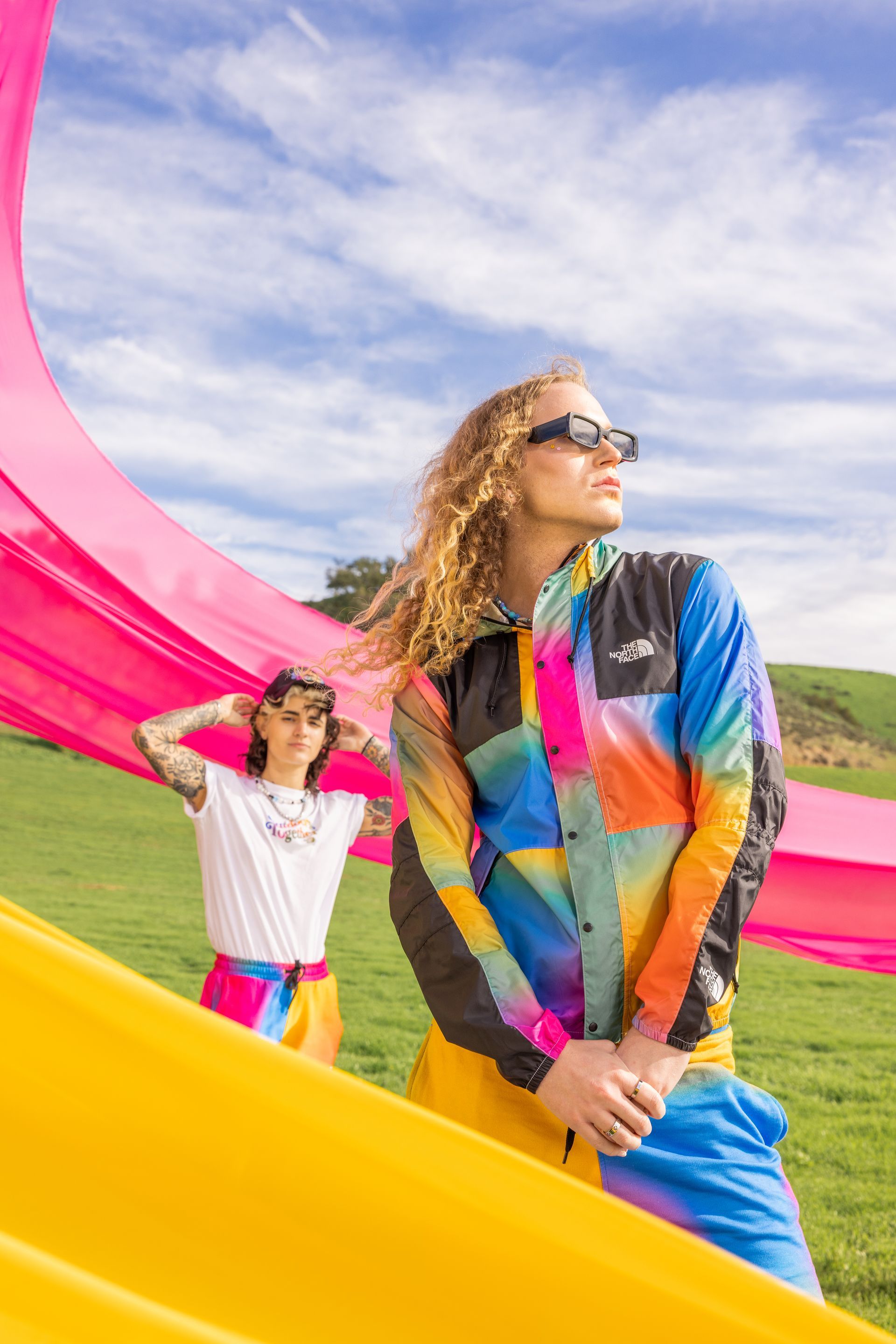 A man and a woman are standing next to each other in a field for a NorthFace photo shoot.
