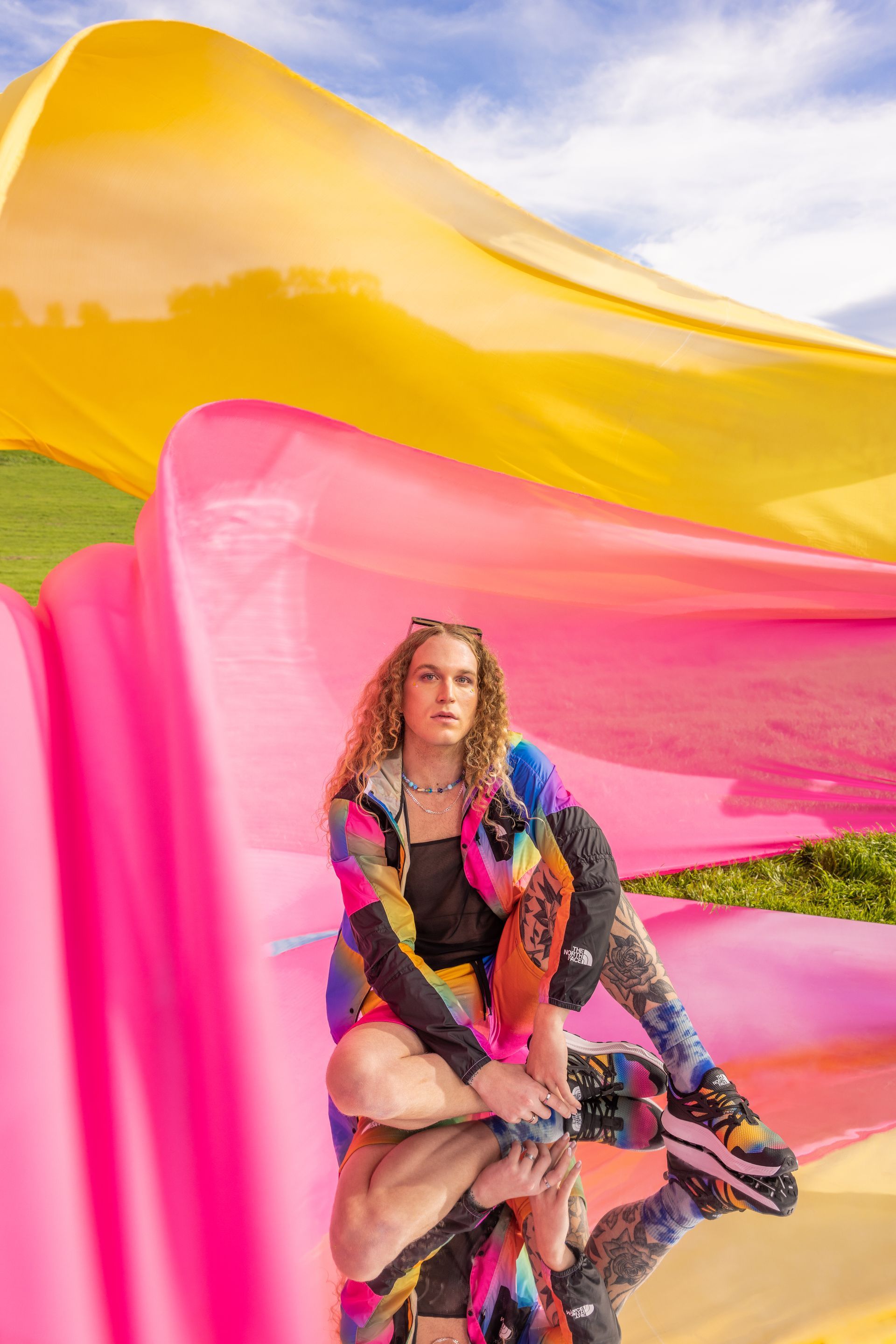 A woman is sitting on a pink and yellow inflatable for a NorthFace photo shoot.