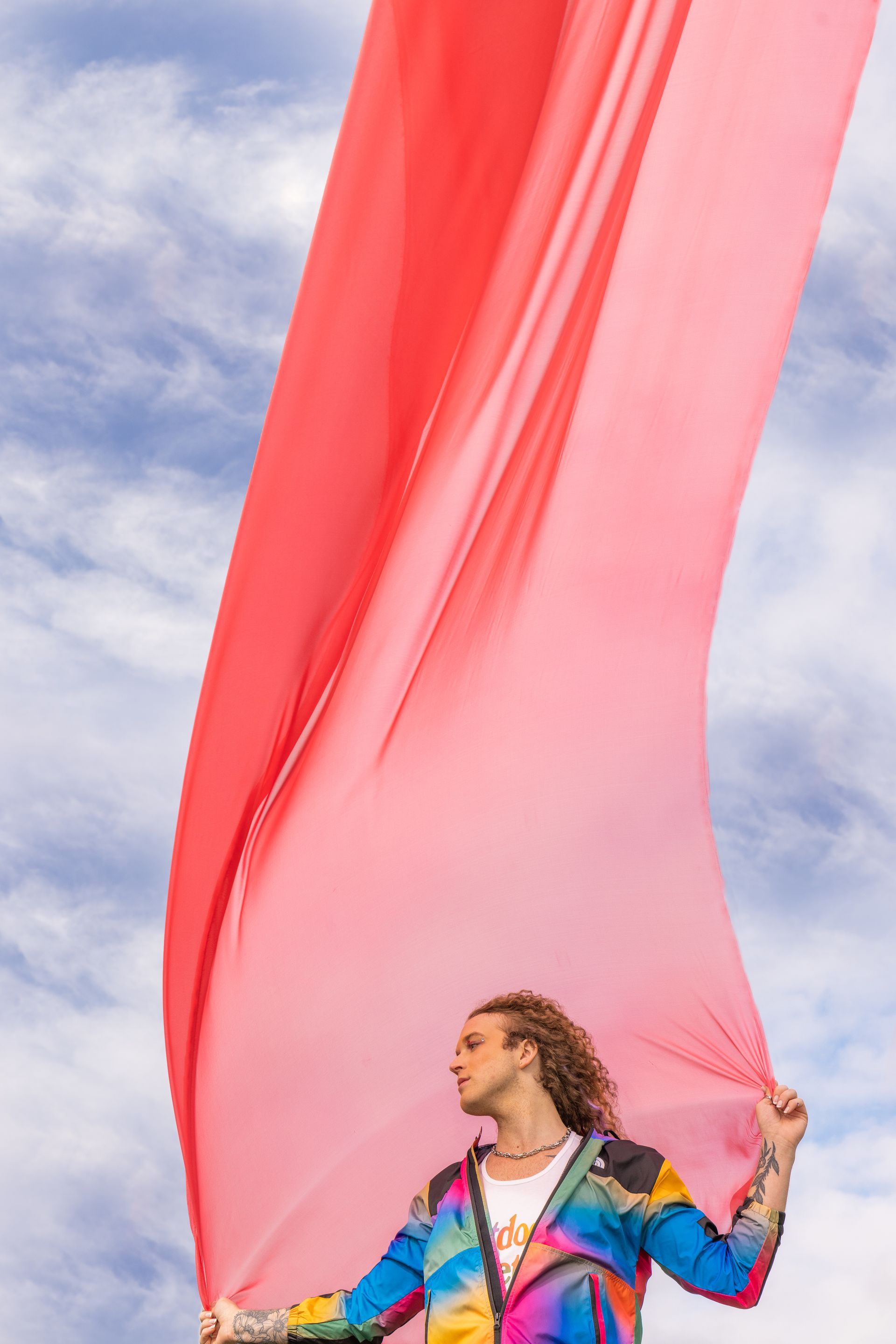 A man in a colorful jacket is holding a red cloth in his hands for a NorthFace photo shoot.