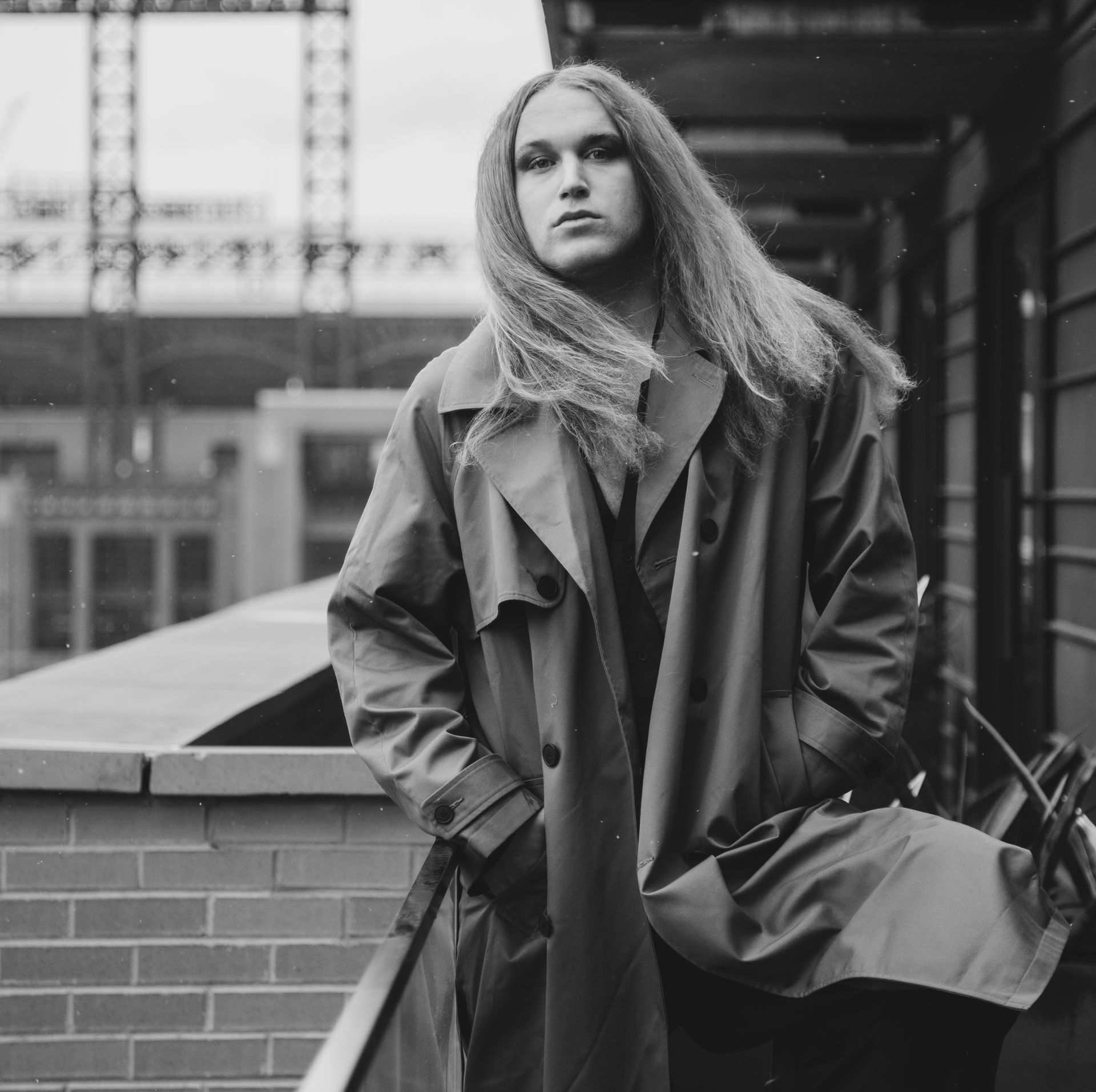 A black and white photo of a person in a trench coat for a photo shoot.