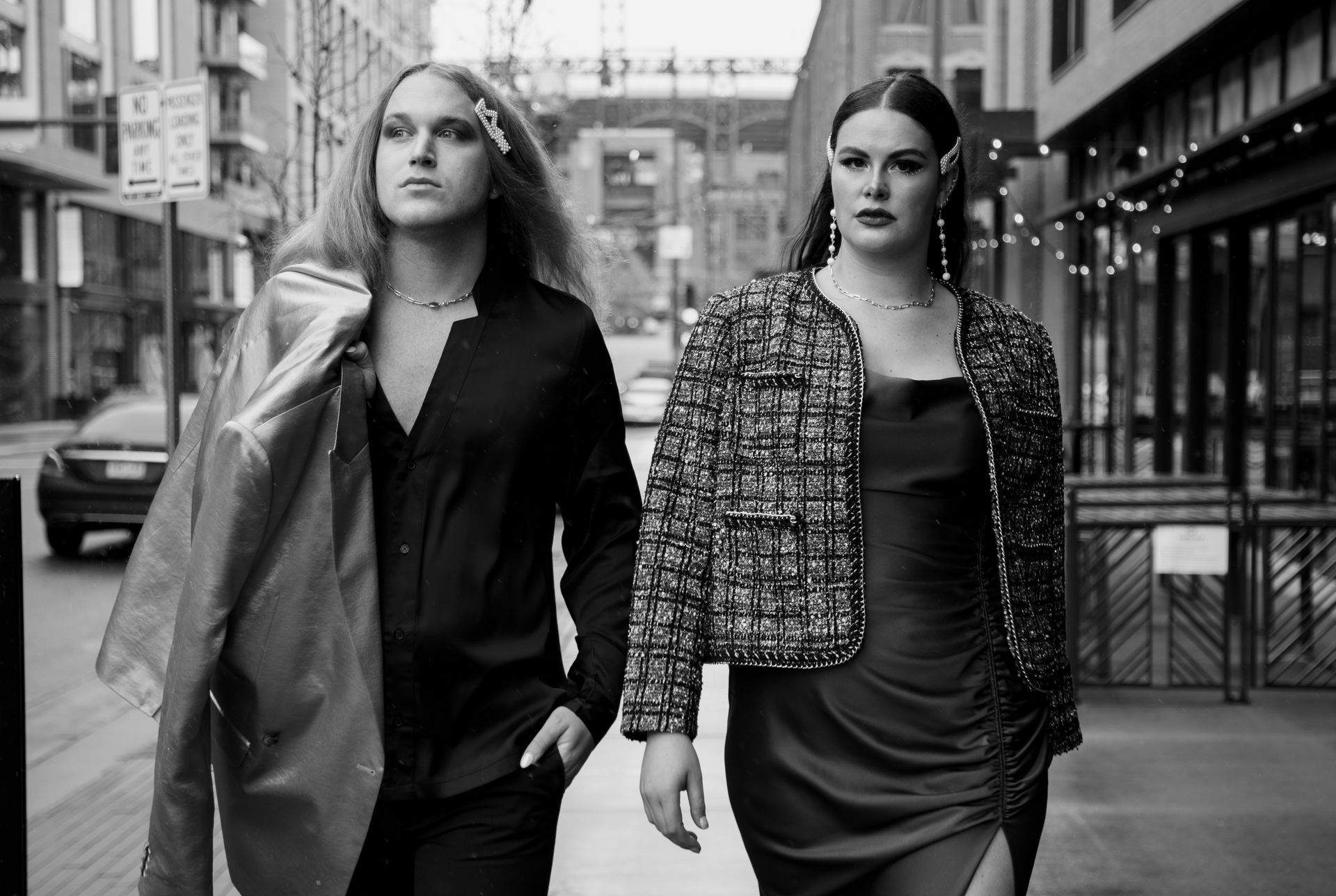 Two women are walking down a city street holding hands for a fashion photo shoot.