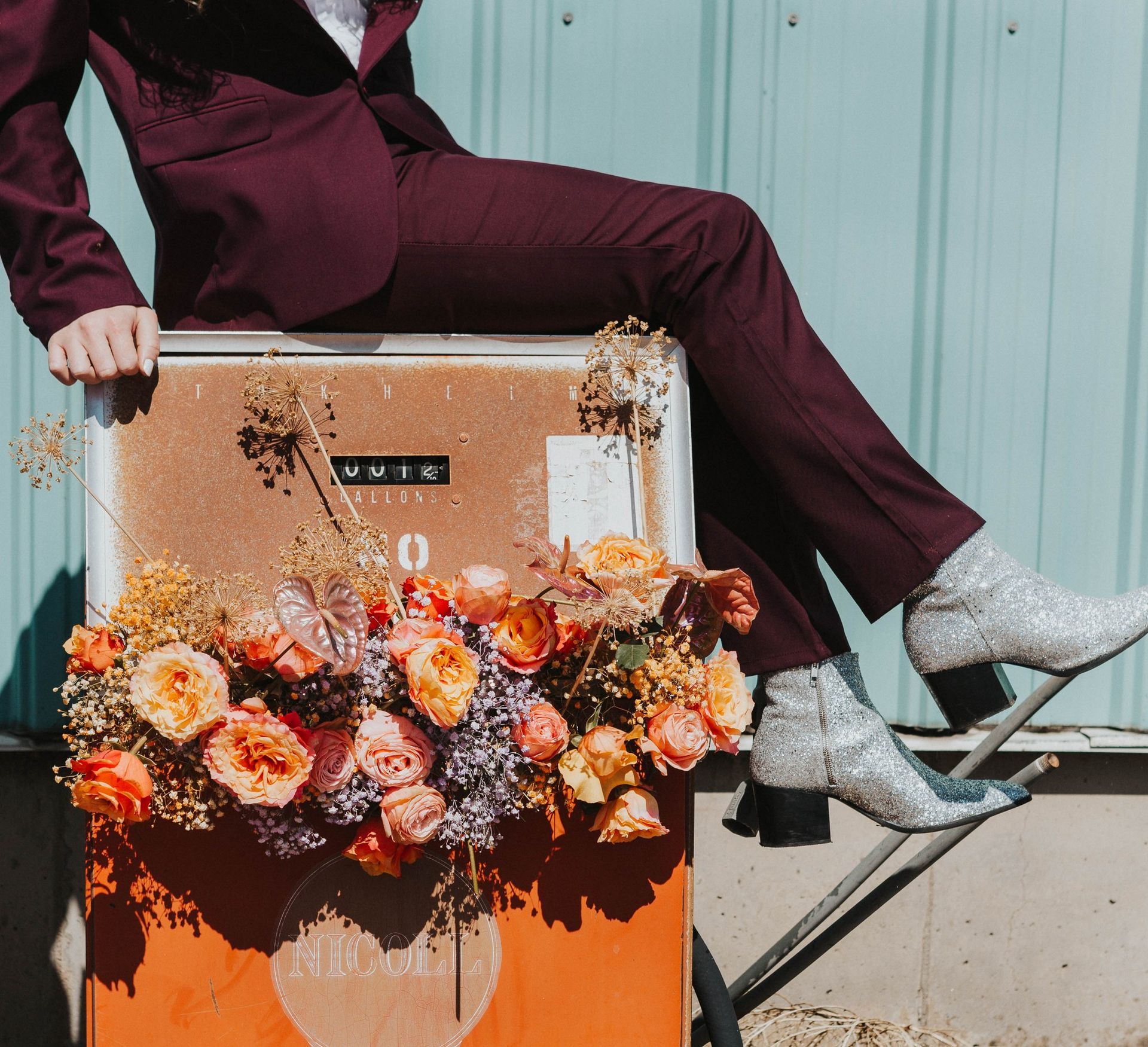 Scotty wearing a maroon suit posing in a car with flowers, modeling for a photoshoot