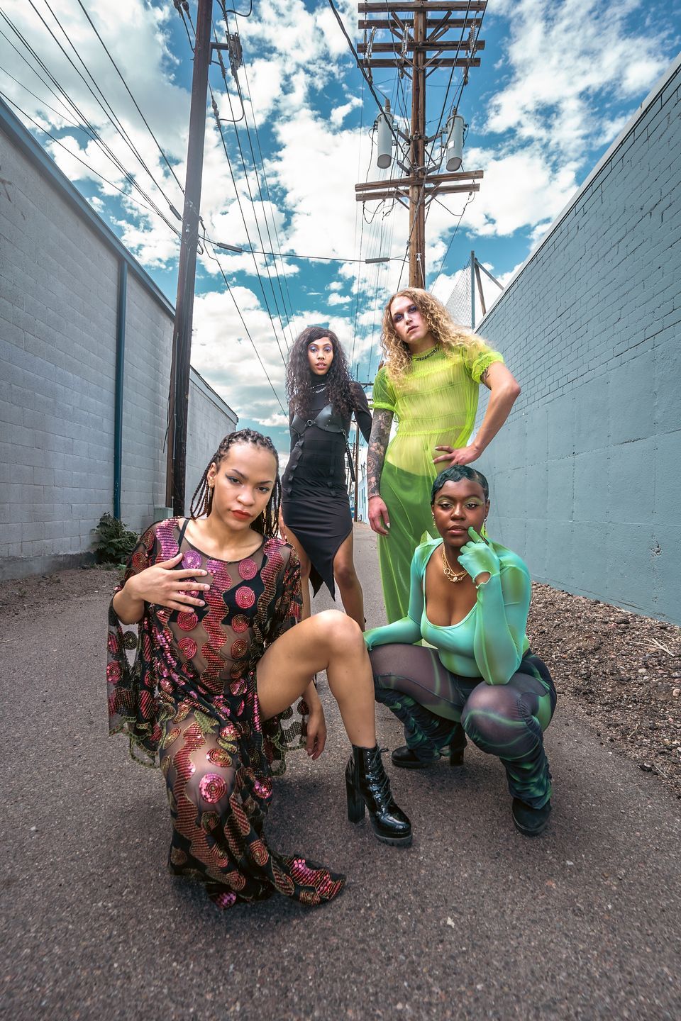 A group of women are posing for a picture in an alleyway for a fashion photo shoot.