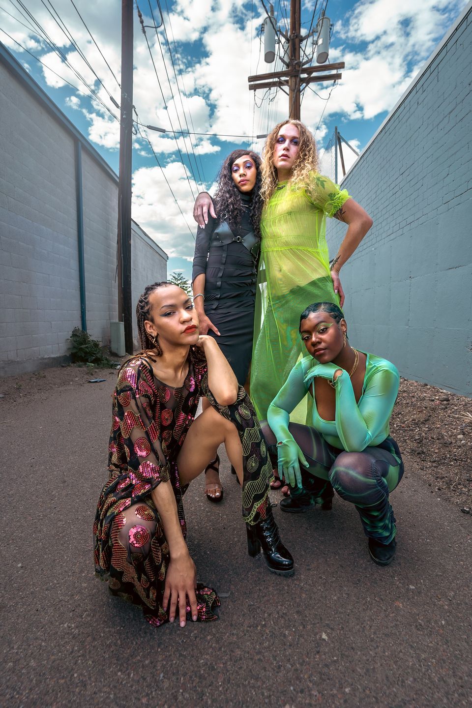 A group of women are posing for a picture in an alleyway for a fashion photo shoot.