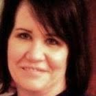 Woman with dark hair and brown eyes smiling slightly.