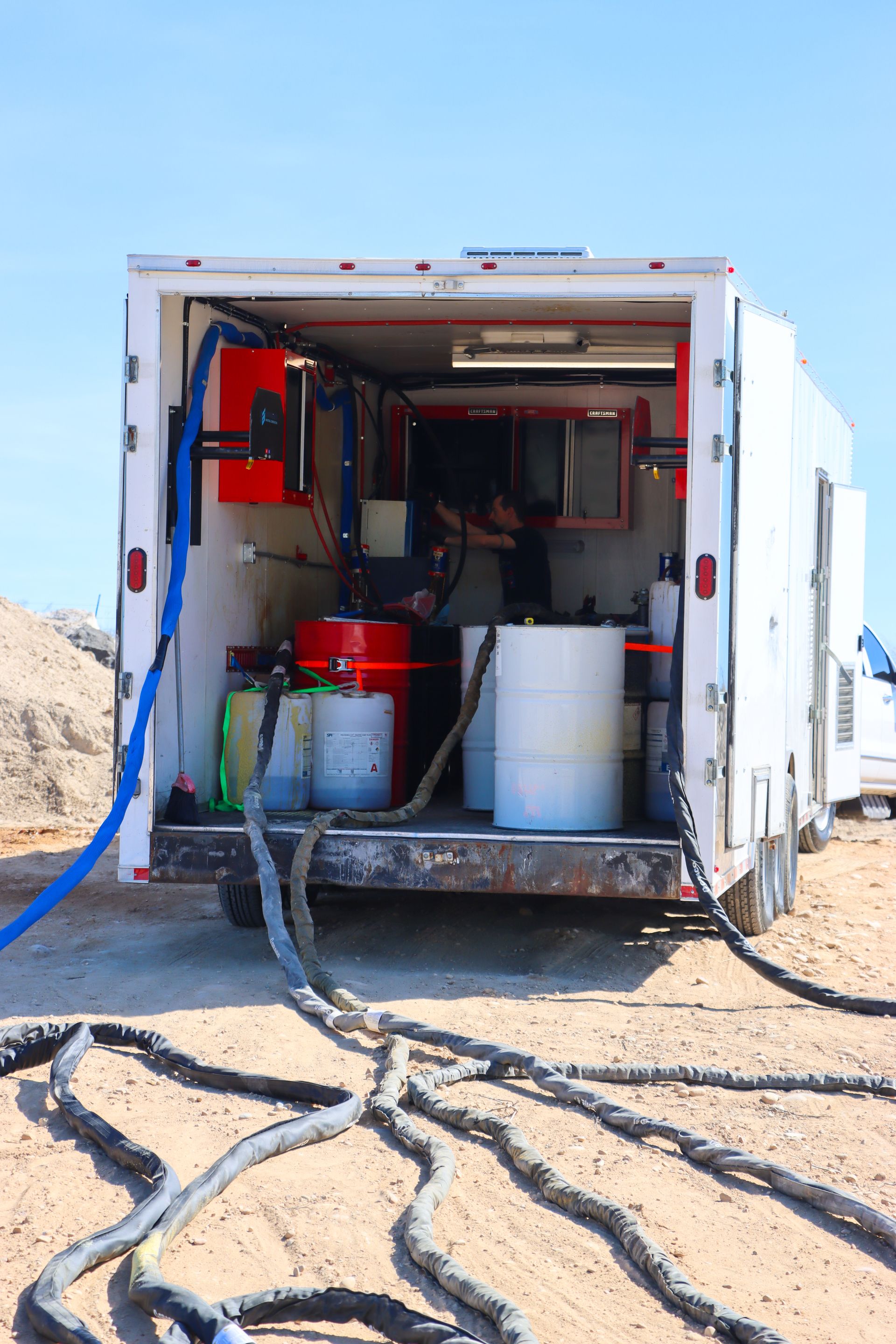A white trailer with a lot of hose attached to it.