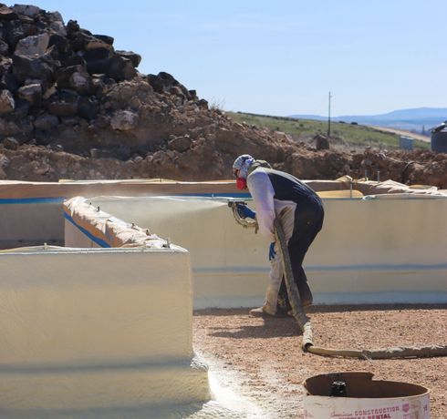 A man is spraying foam on a concrete wall