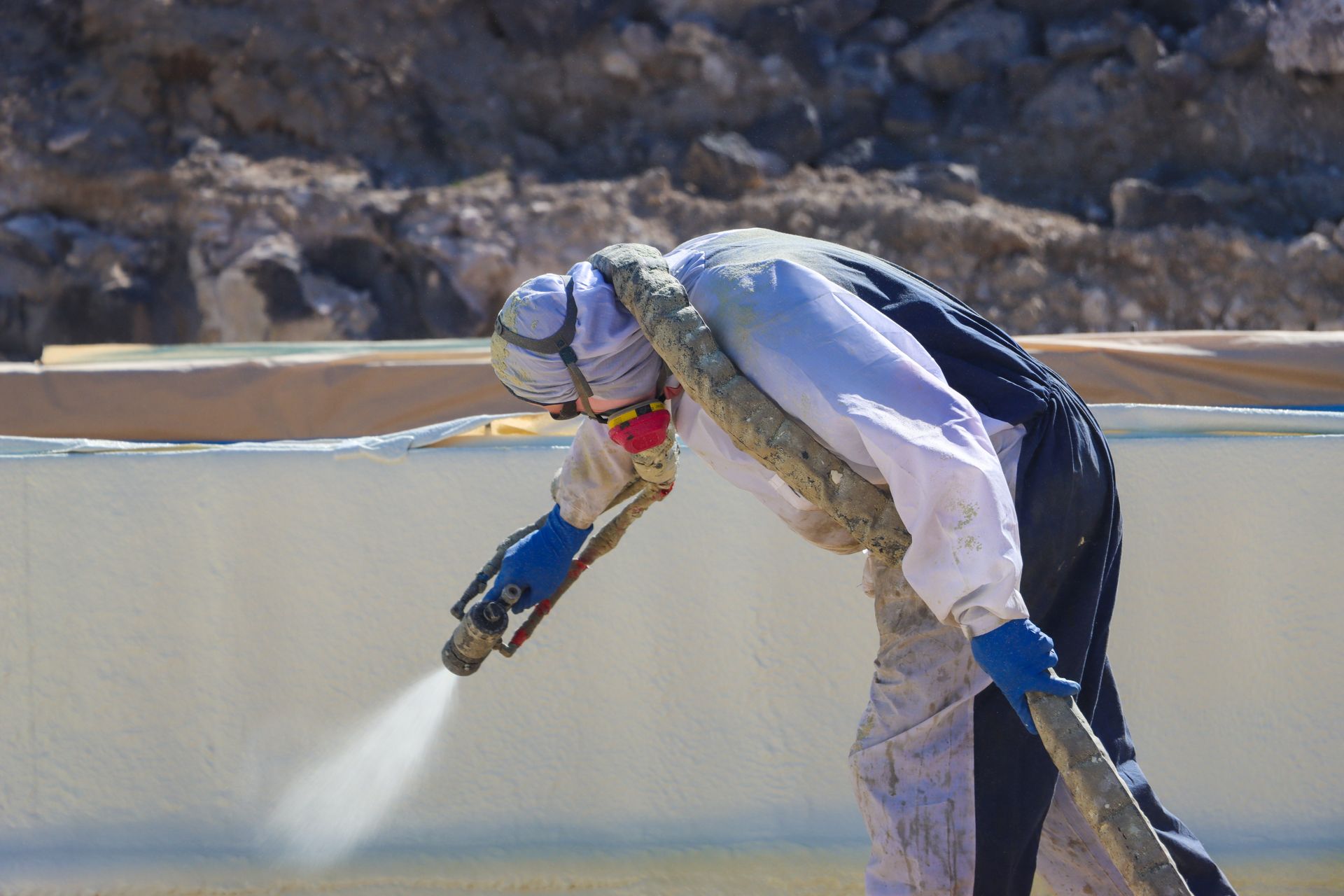 A man is spraying foam on a wall.