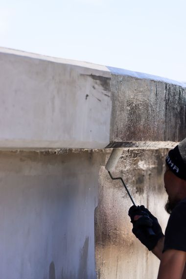 A man is painting a wall with a roller.