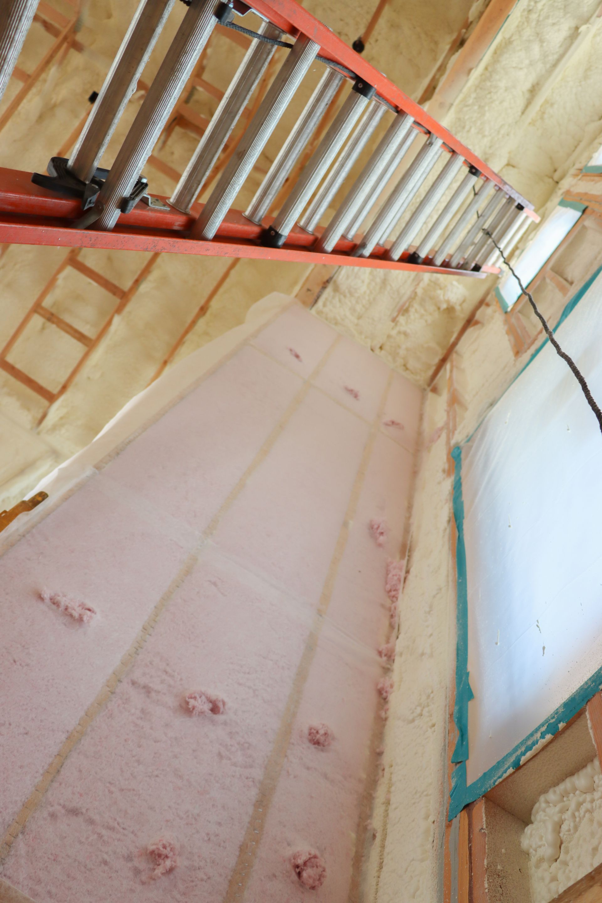 A person is spraying foam on a wooden wall.