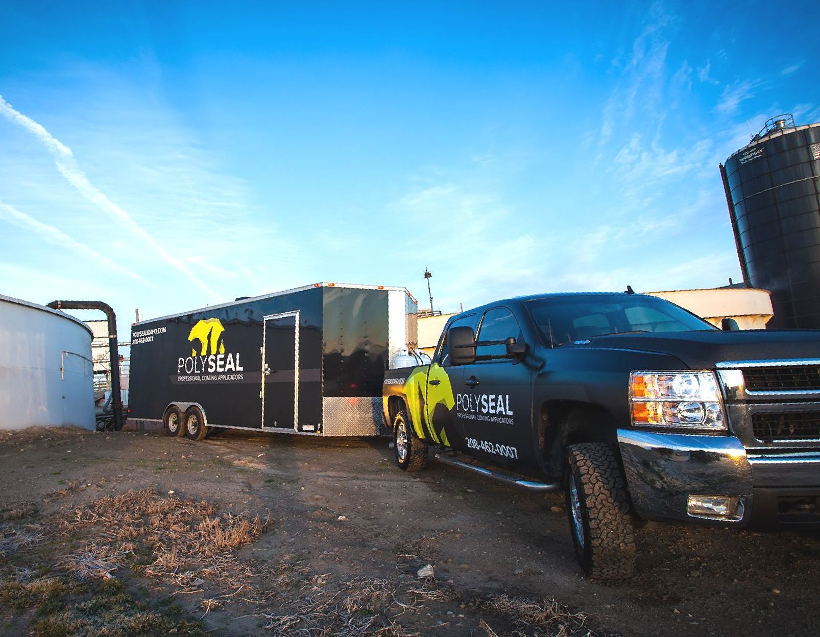 A black truck is parked next to a black trailer