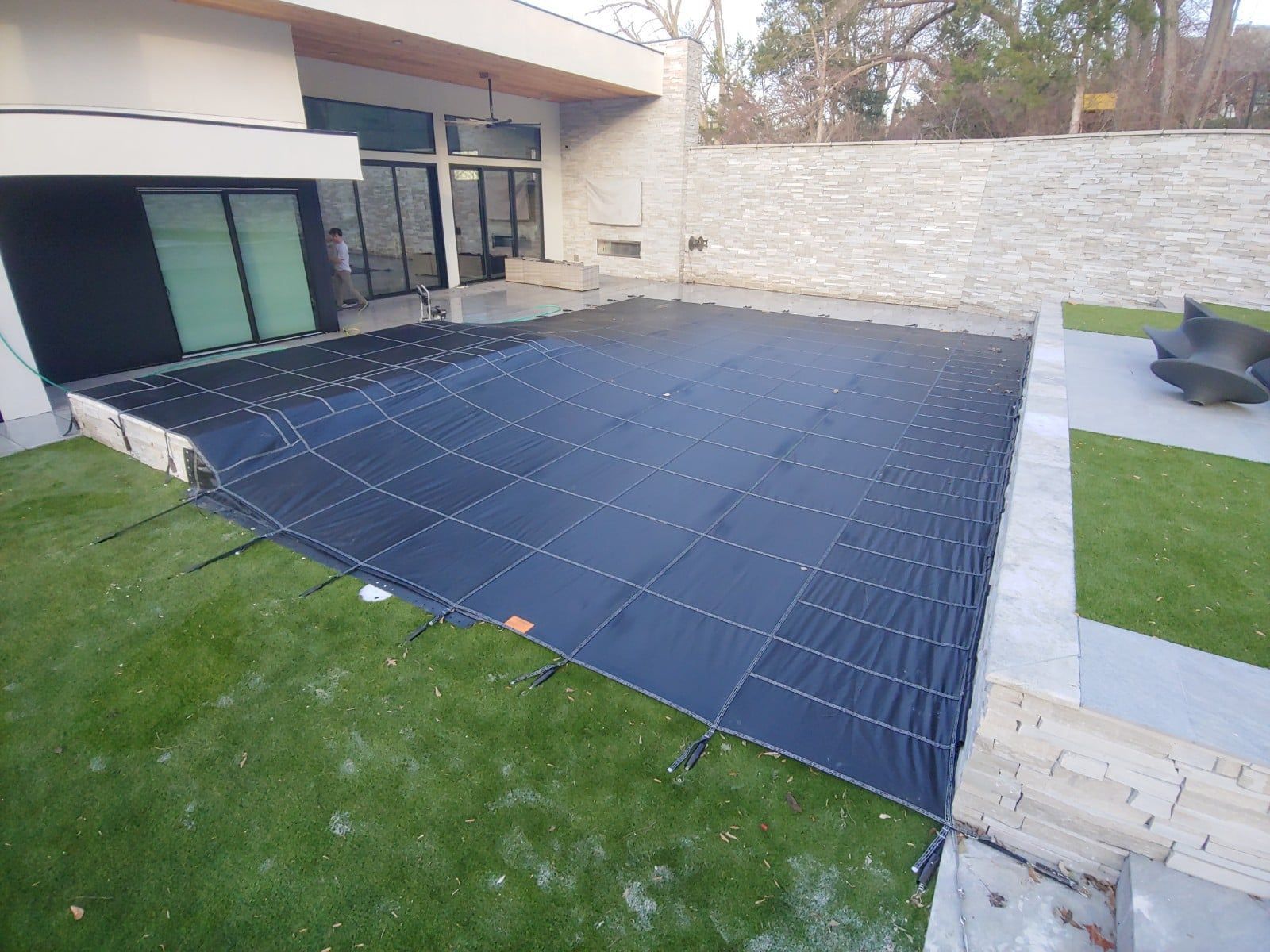 A rectangular swimming pool covered with a black safety net