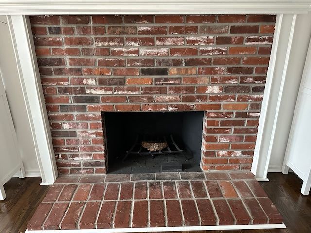 Brick fireplace with white trim, dark firebox, and a brick hearth.