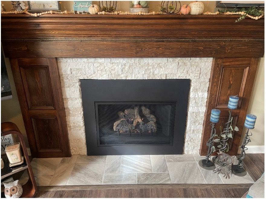 Fireplace with wooden mantel, light stone surround, black insert, and tile hearth.