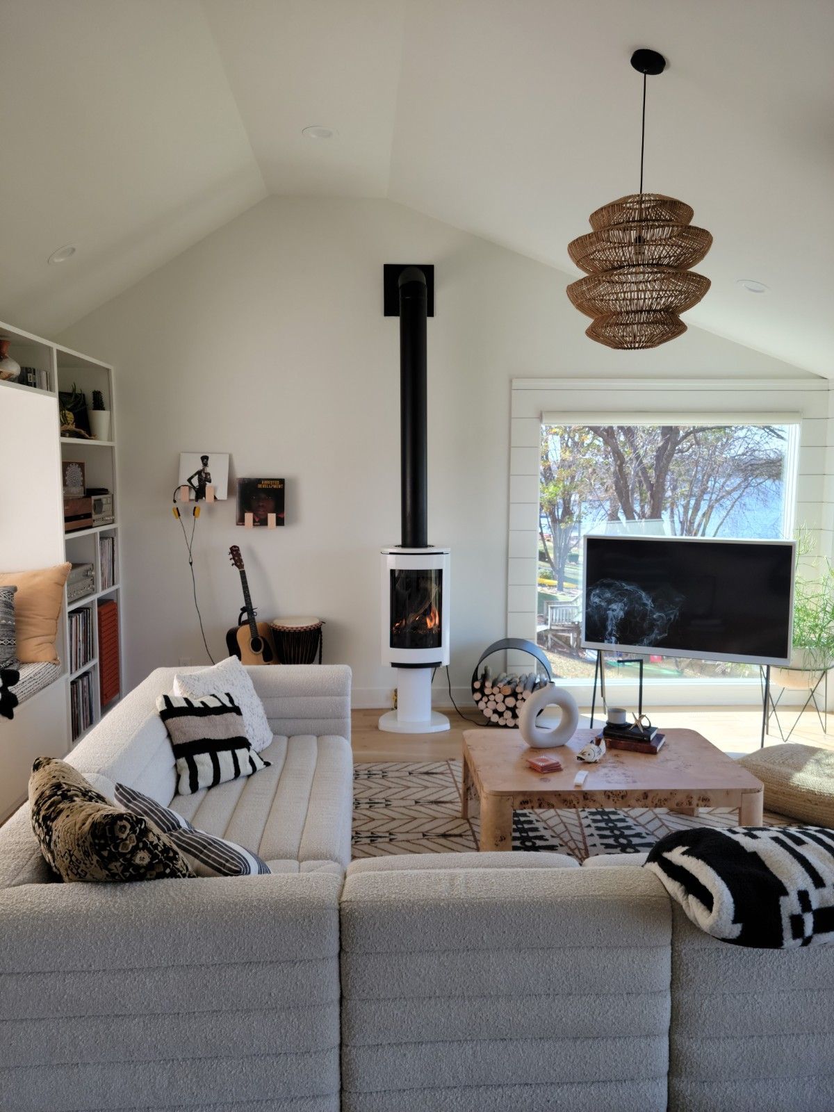 Cozy living room with white couch, fireplace, wooden coffee table, and large window overlooking a view.