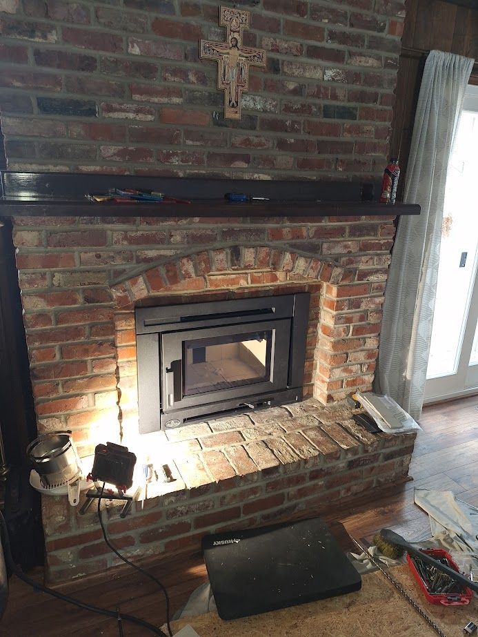 Brick fireplace with dark insert and wooden mantel; crucifix above.