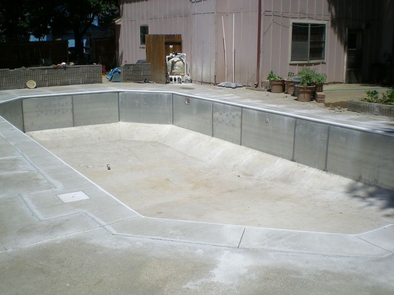 Empty concrete swimming pool under construction, viewed from the side.