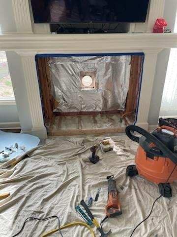 Fireplace renovation in progress; interior lined with foil. Tools and drop cloth visible.