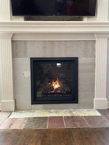 Fireplace with flames in a black surround, surrounded by light gray, and beneath a mounted TV.