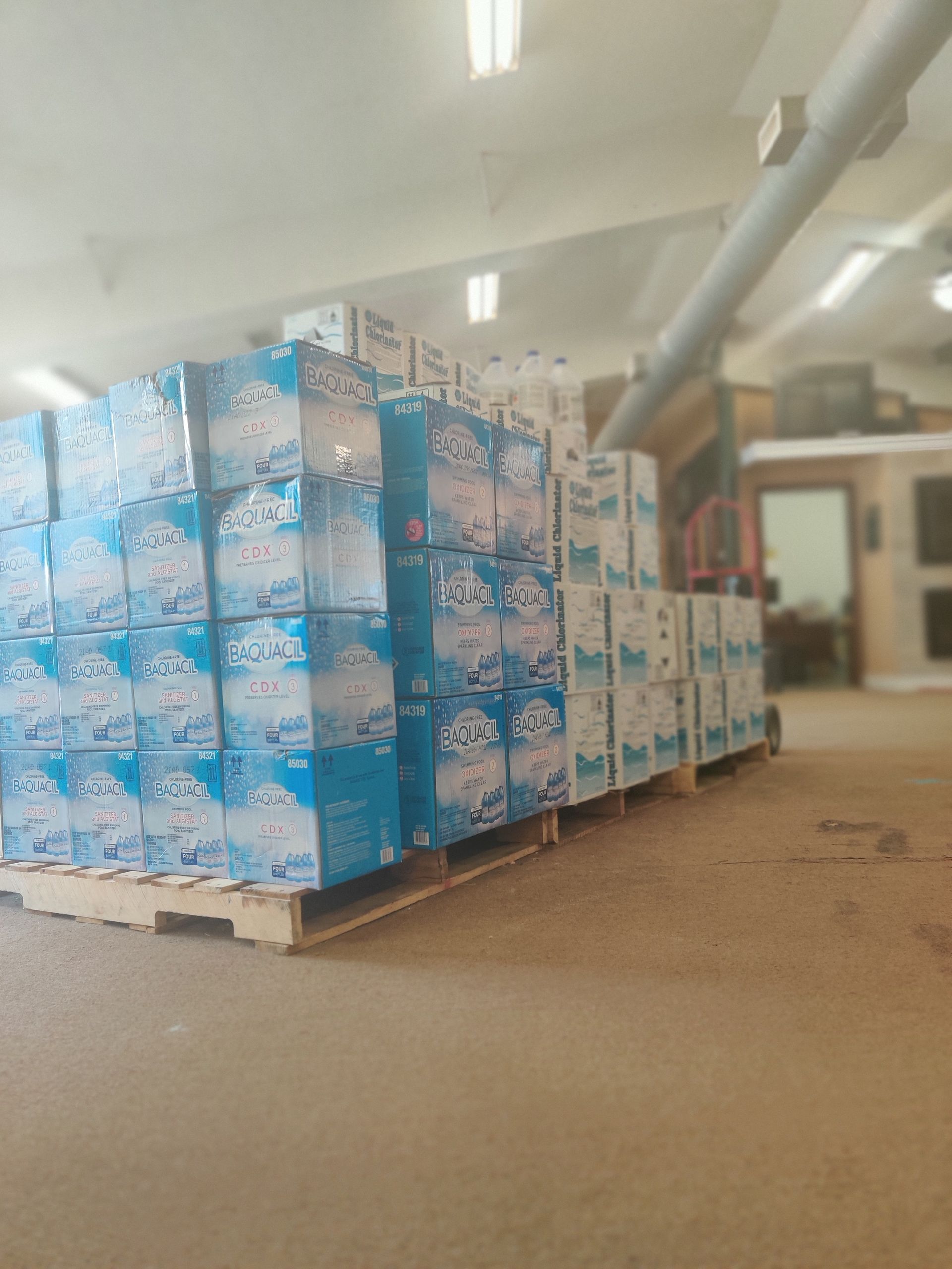 Pallet of stacked blue and white water bottle boxes in a warehouse setting.