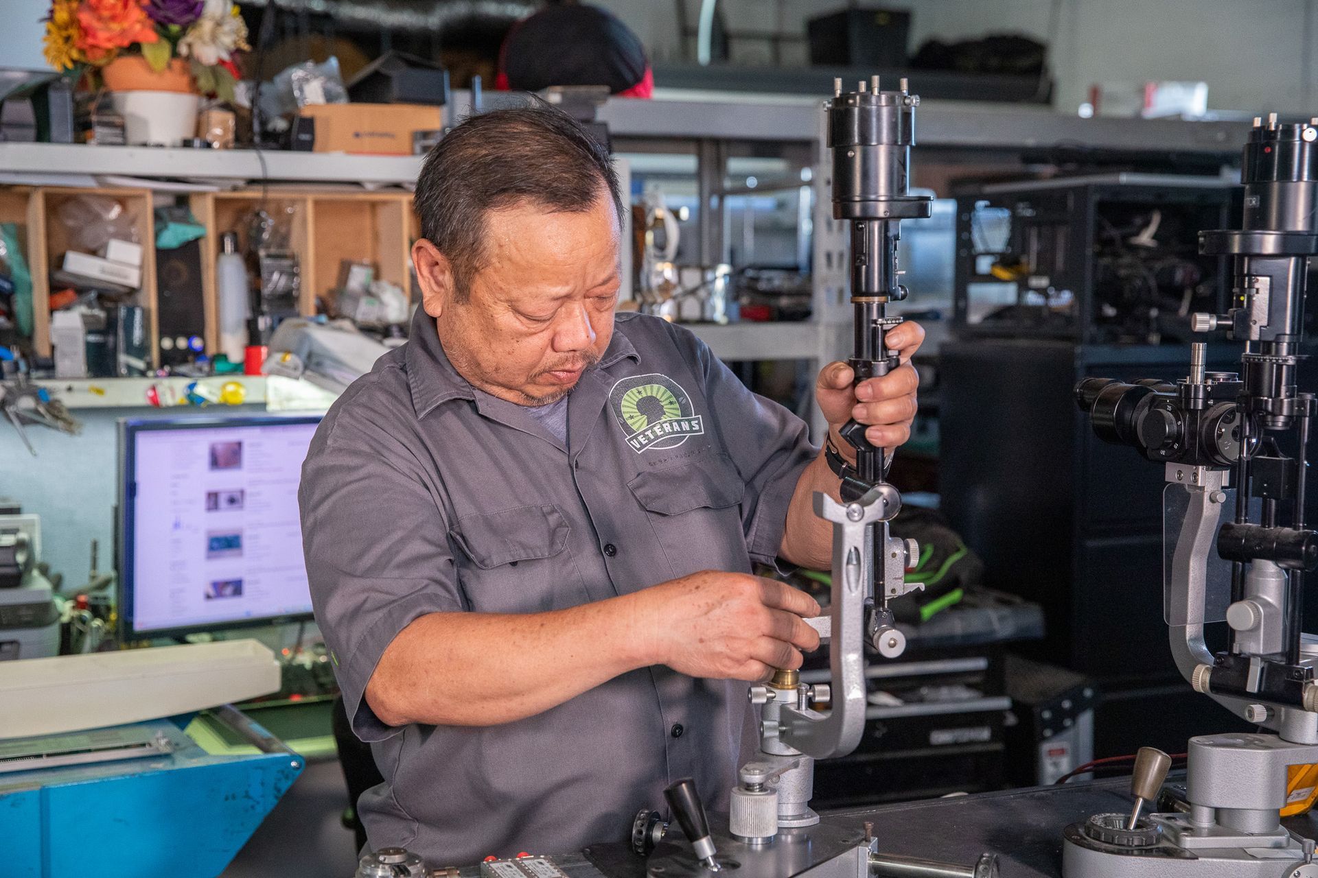 Mechanic in gray shirt working on machinery in a workshop. He's concentrating while adjusting parts.