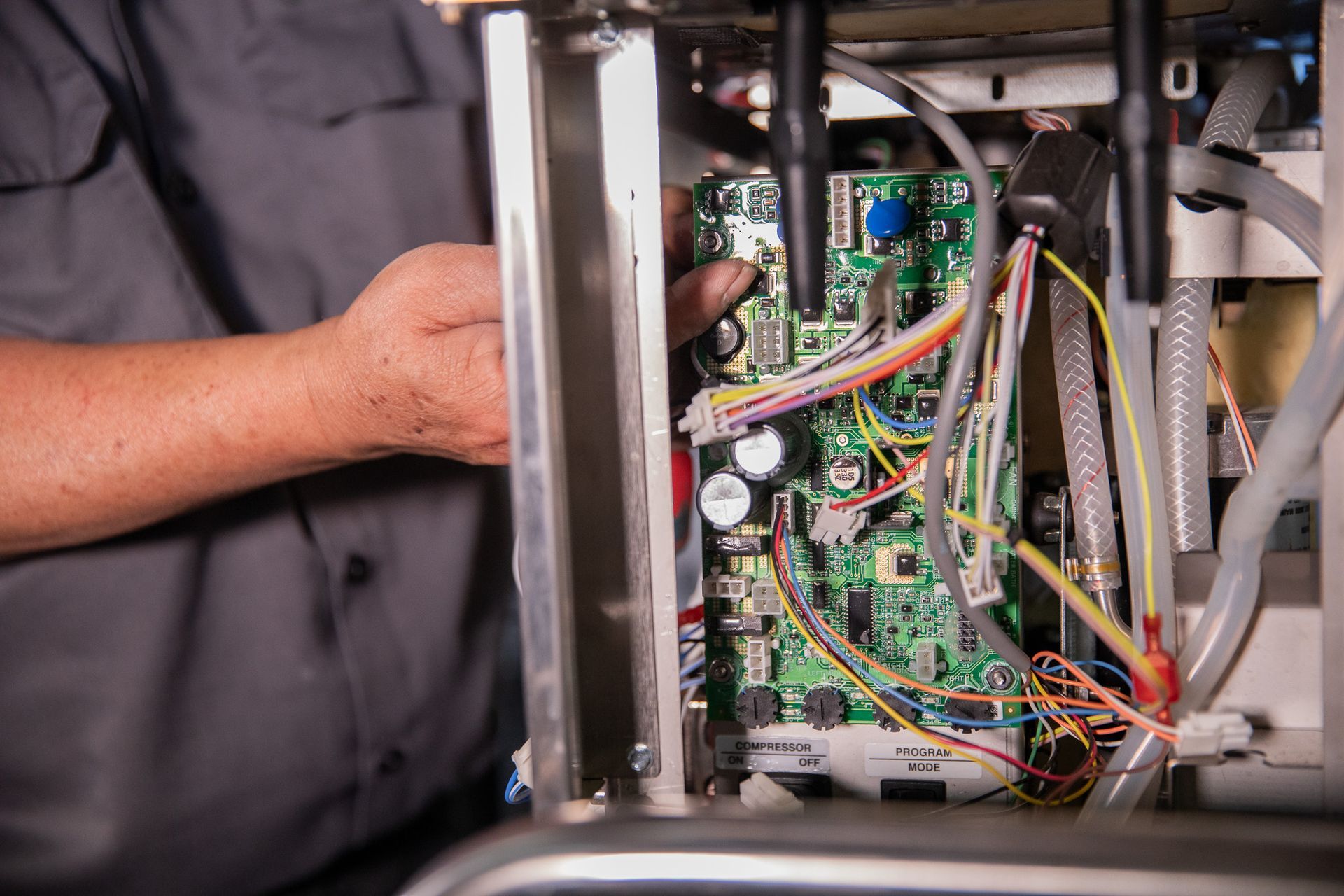 Person fixing circuit board inside metal machine.