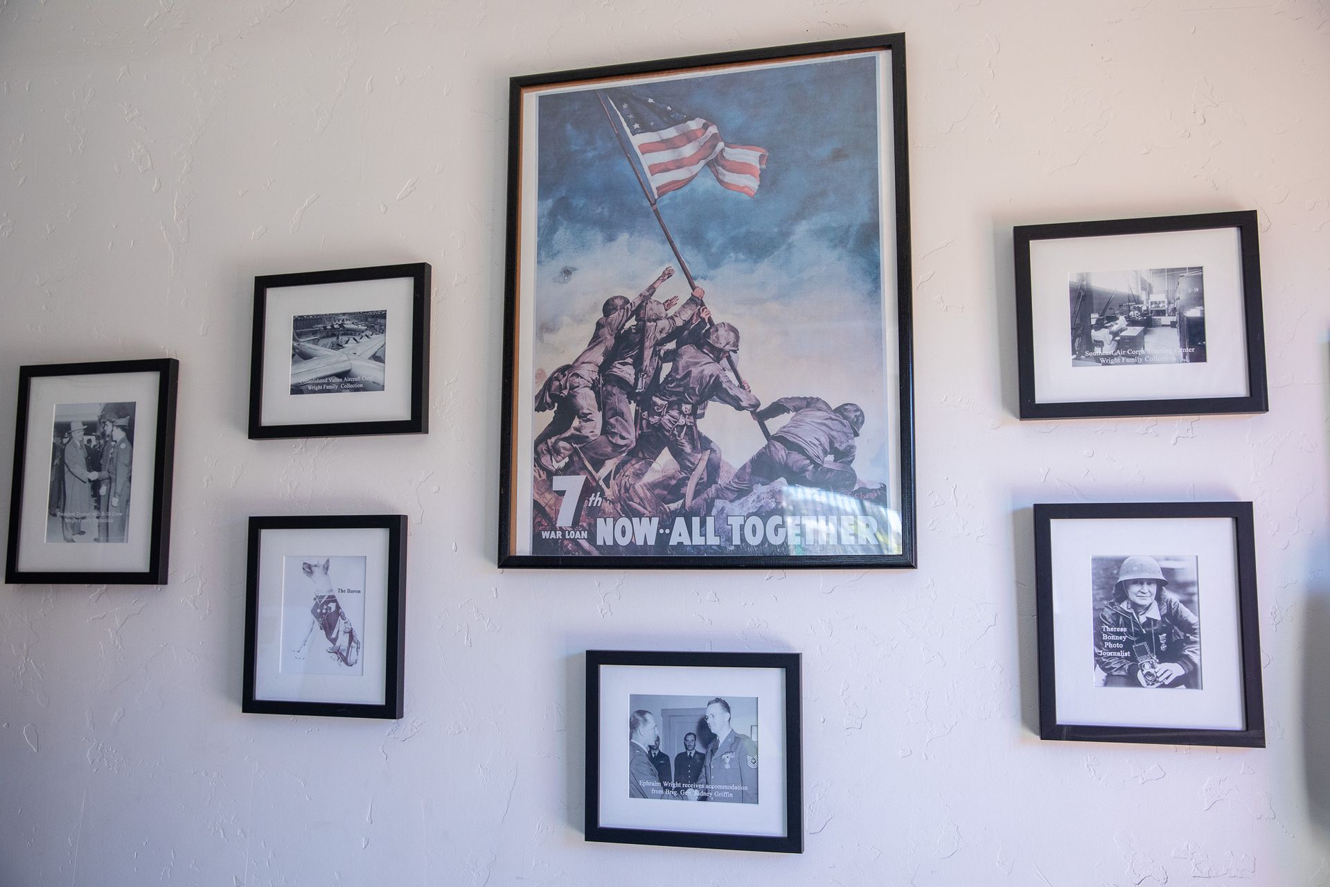 Wall with framed black and white photos and a large framed 