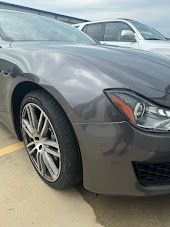 Gray Maserati car parked outside, with a white SUV in the background | Axe-A-Dent Auto Collision