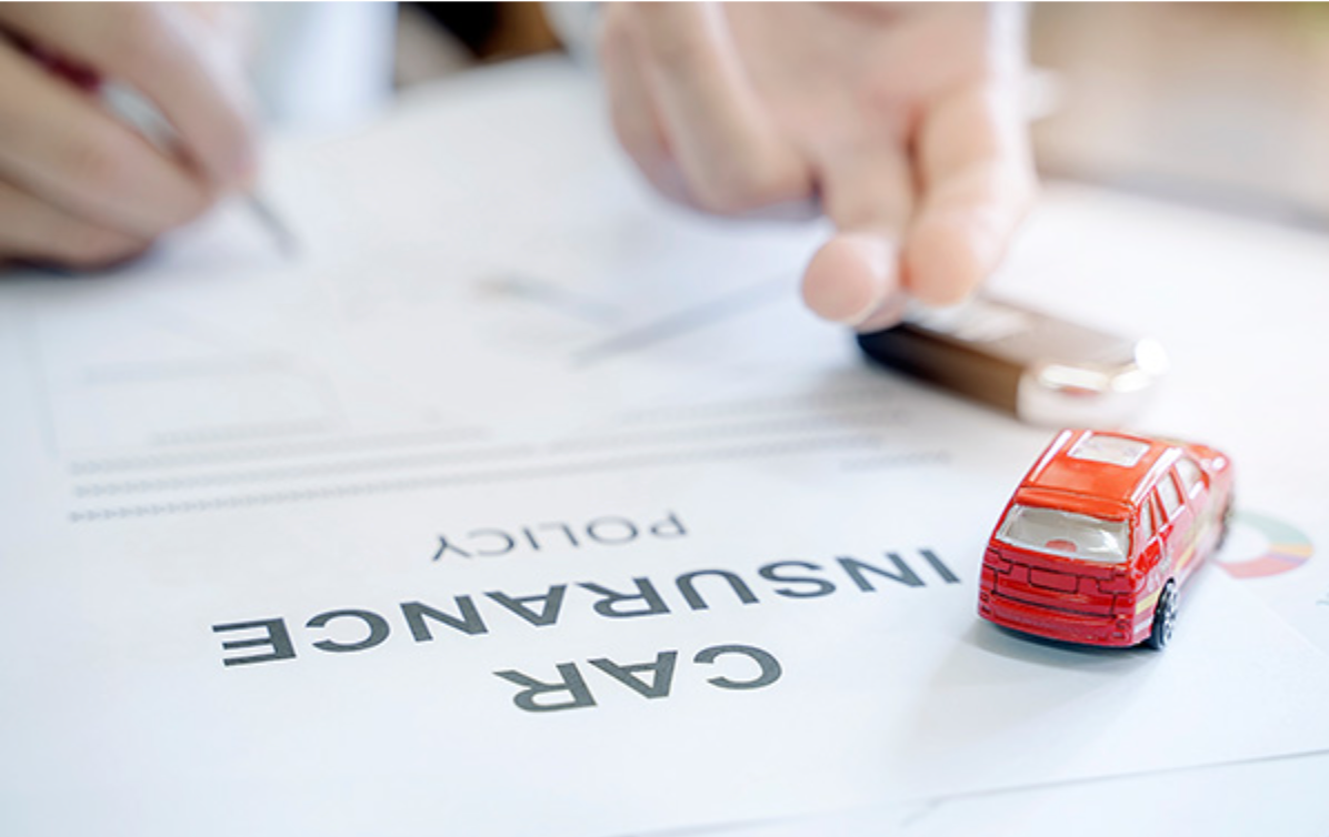 Person signing car insurance policy, with toy car and keys on document | Axe-A-Dent Auto Collision