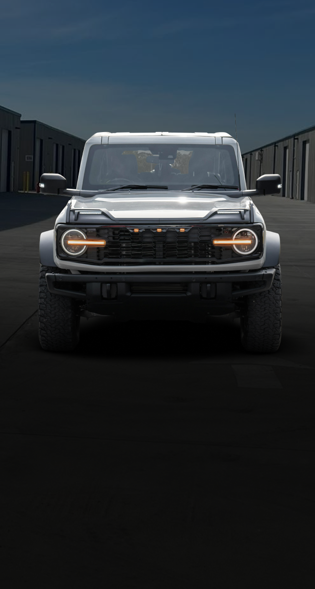 Gray Ford Bronco SUV facing forward, parked between dark warehouse buildings | Axe-A-Dent Auto Collision