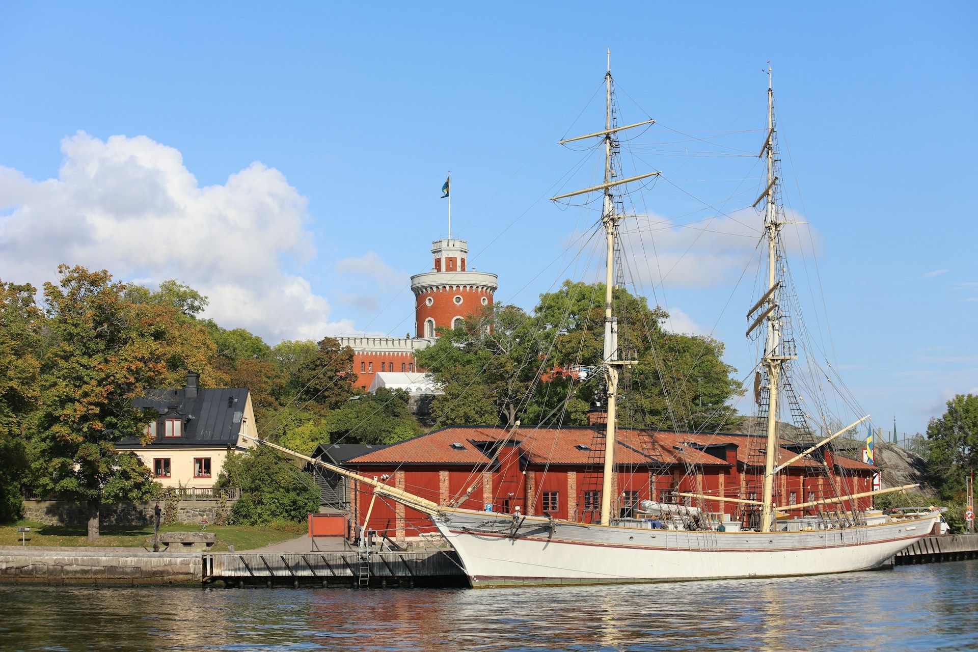 A white two-masted sailing ship docked at the island of Skeppsholmen in Stockholm.