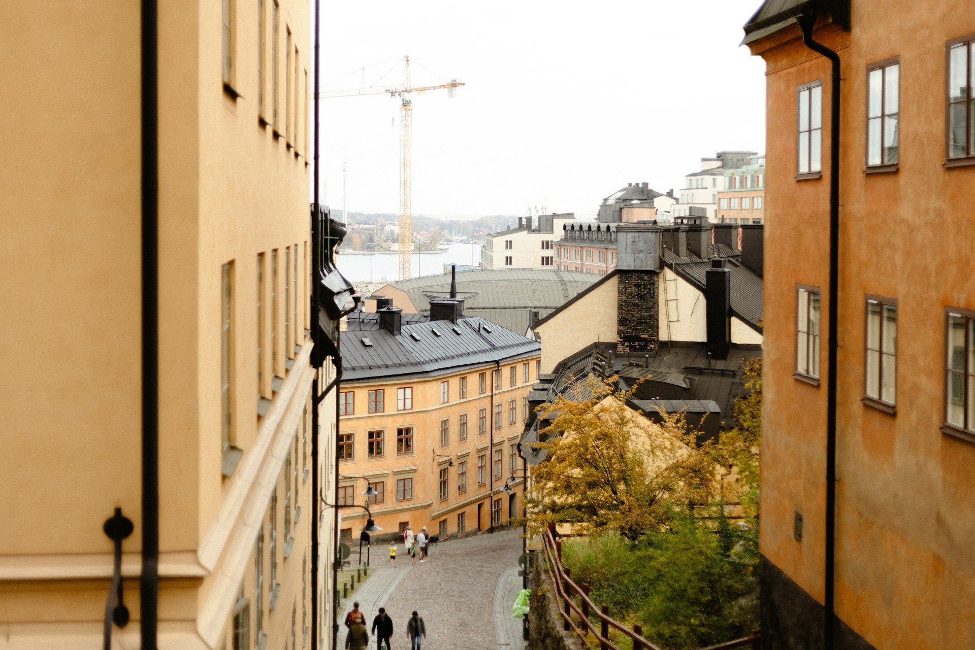 A view down a cobbled street in Stockholm, framed by tall ochre buildings.