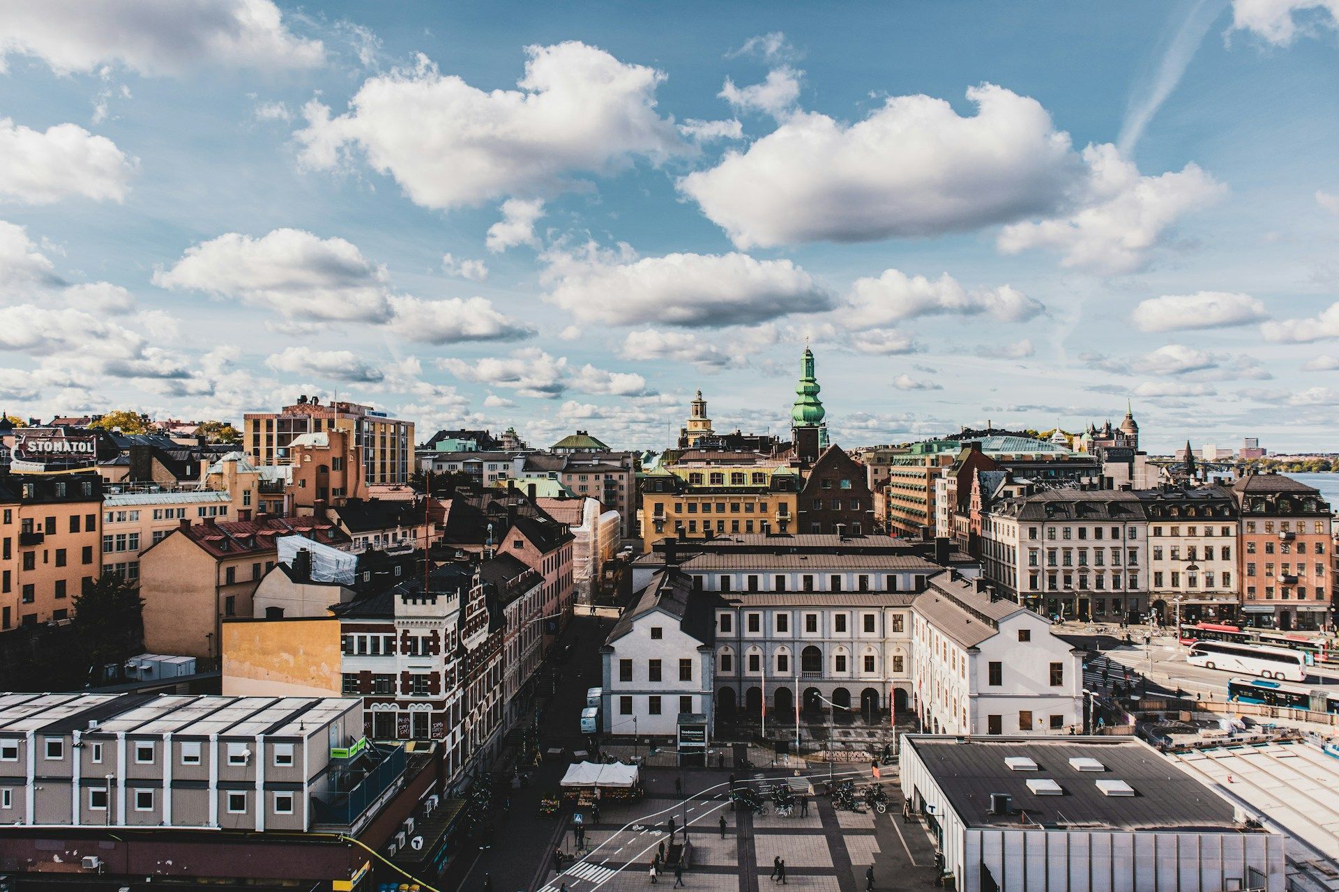 A high-angle view of Stockholm, Södermalm, featuring colorful buildings and a church steeple under a cloudy sky.